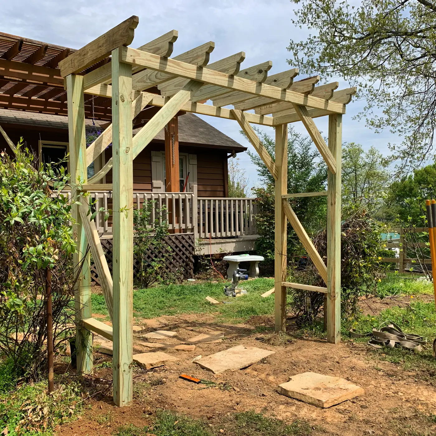 Wood pergola with open rafters over a stone garden path